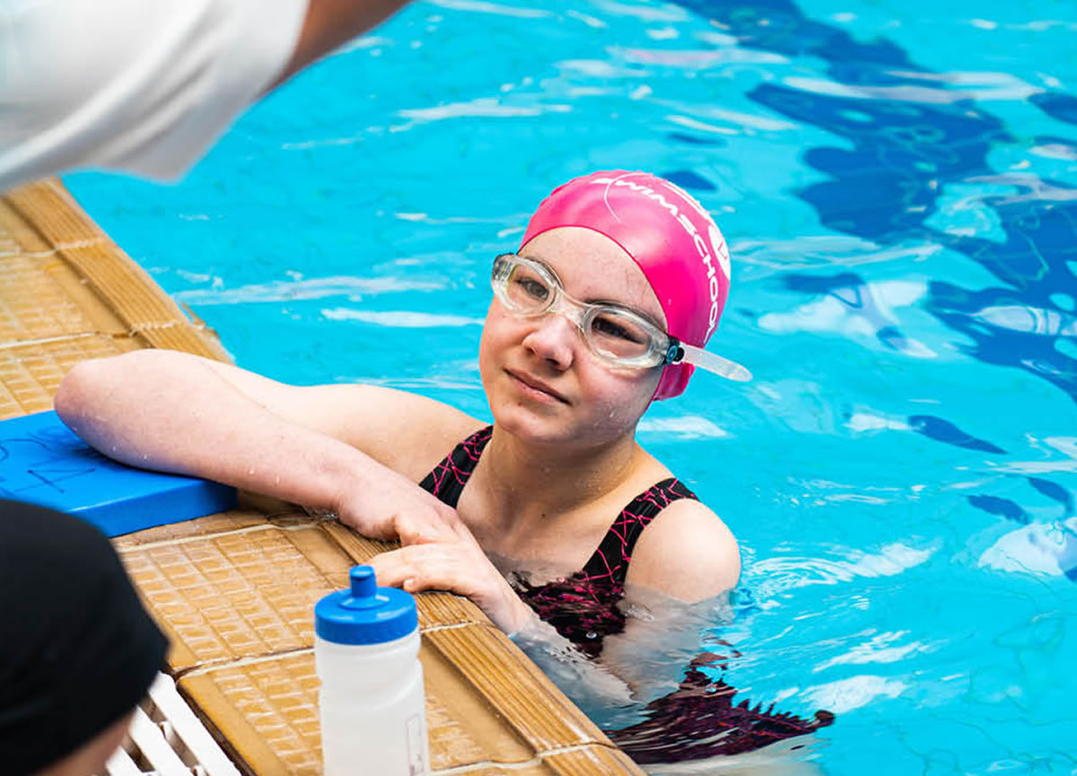 Image of an S4 swimmer on the pool edge with an S4 instructor