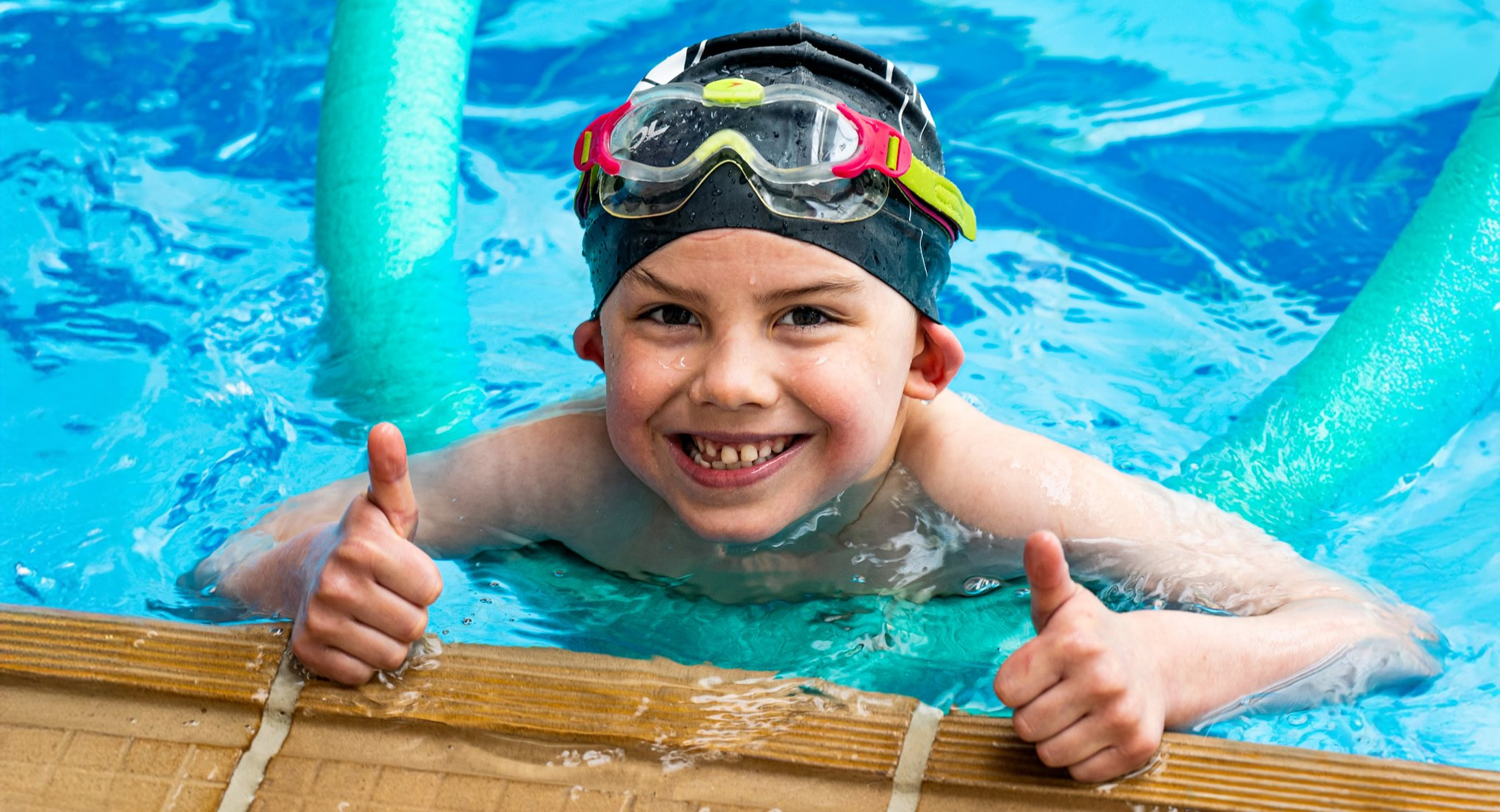 An image of a happy S4 swimmer at the side of a swimming pool.